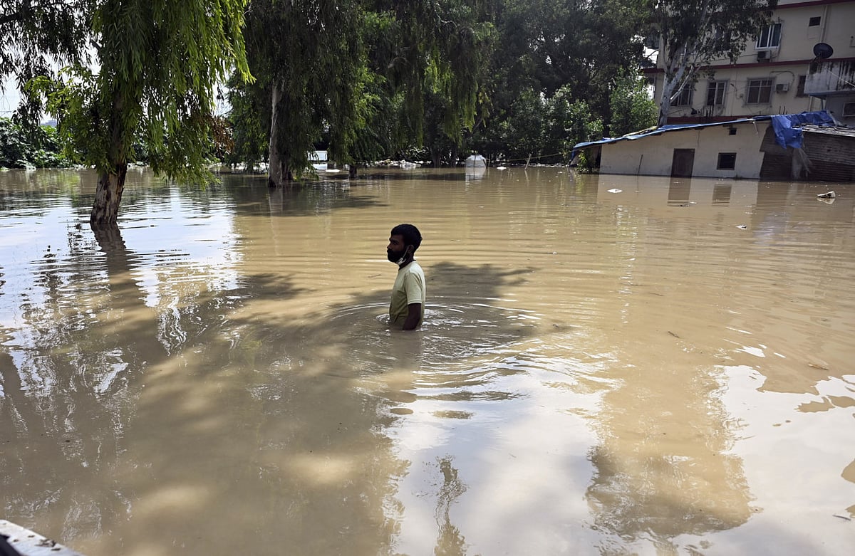 A man wades through water following the rise in water level of the Yamuna river, near ISBT in New Delhi on September 3, 2025.  