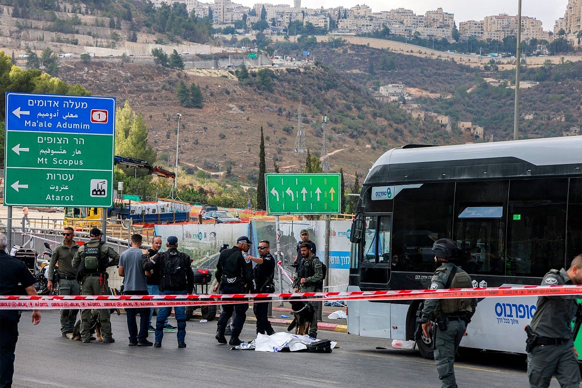Israeli security forces gather by a body next to a bus at the Ramot road junction in Israeli-annexed east Jerusalem on September 8, 2025.