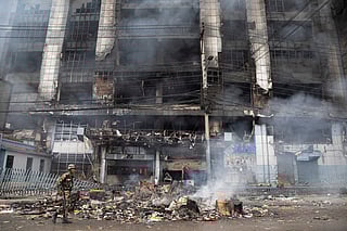 An Army personnel patrols along a street as smoke billows from a burning supermarket building of Nepal's renowned retail chain Bhat-Bhateni, a day after it was set ablaze by protesters in Kathmandu on September 10, 2025.