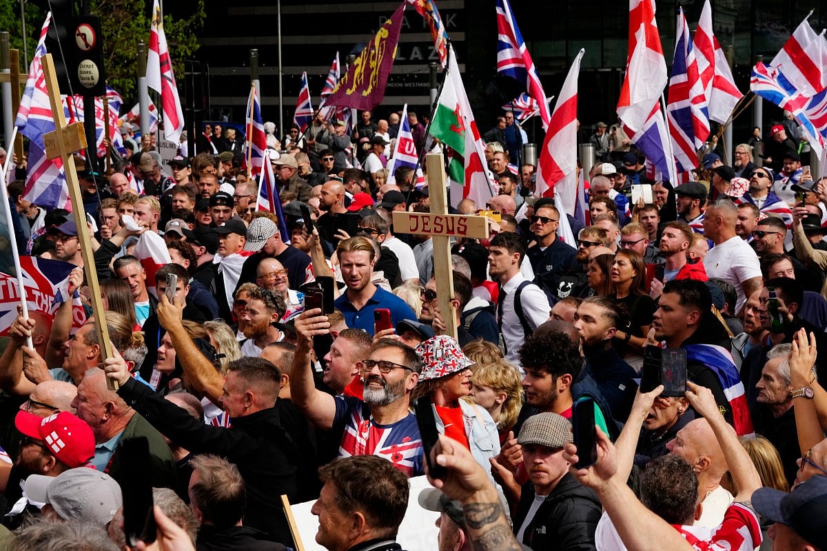 Supporters of British far-right activist Tommy Robinson, whose real name is Stephen Yaxley-Lennon, walk with Union flags and St George's cross and Welsh flags and Christian crosses through central London during a 'Free speech' march, on September 13, 2025.