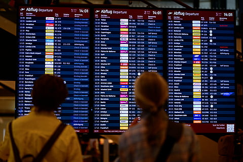 Passengers check a digital display showing status of outgoing and incoming flights.