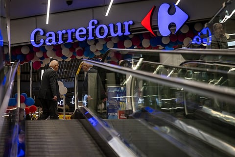 People pass-by the logo of the French supermarket chain Carrefour at the entrance to the store in the shopping mall in the Warsaws downtown, Poland, on September 22, 2025.