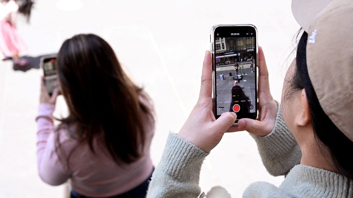 A file photo taken on November 28, 2024 shows young people looking at their phones in Melbourne as Australia looks to ban children under 16 from social media.