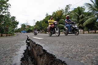 Motorists pass a crack in the road along a major highway in Tabogon town, Cebu province.