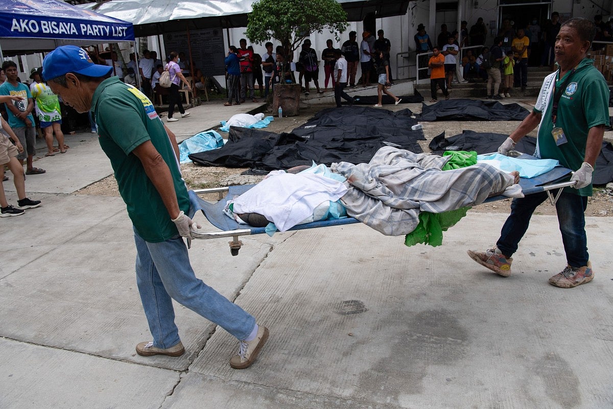 Workers carry a deceased person on a stretcher past bags containing the dead bodies of victims outside the provincial hospital in Bogo City on October 1, 2025, after a powerful 6.9 magnitude earthquake jolted the central Philippines, killing at least 31 people on the island of Cebu with fears the toll could rise.
