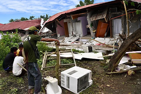 People inspect a collapsed building where three people were reported missing in Bogo City.
