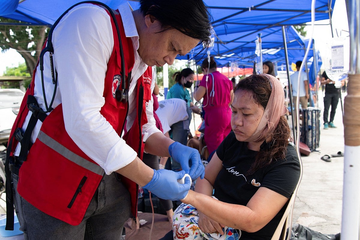Injured people receive treatment at a makeshift emergency station outside the provincial hospital in Bogo City .