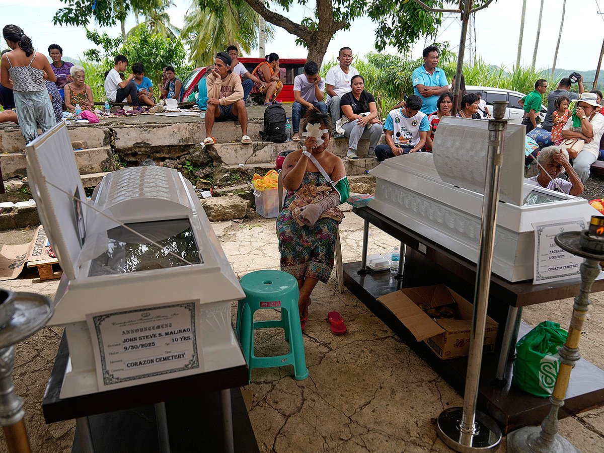 Earthquake survivor Jesiel Malinao sits beside the coffins of her two sons on Thursday, Oct. 2, 2025 after a strong earthquake on Tuesday caused a landslide that toppled their hillside homes in Bogo city, Cebu Province, Central Philippines. 