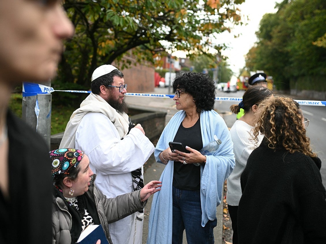 Members of the local Jewish community wait at a police cordon near Heaton Park Hebrew Congregation synagogue in Crumpsall, north Manchester, 
