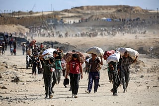 Palestinians carry bags as they leave a food distribution point run by the US and Israeli-backed Gaza Humanitarian Foundation (GHF) group, near the Netsarim corridor in the central Gaza Strip on October 5, 2025. A senior Hamas official on October 5 said the Palestinian militant group is eager to reach an agreement to end the war and implement a prisoner swap with Israel, as negotiators converge in Egypt for talks.