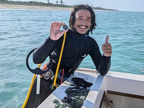 Diver Levin Shavers shows coins uncovered from a Spanish shipwreck off the Atlantic coast of Florida.