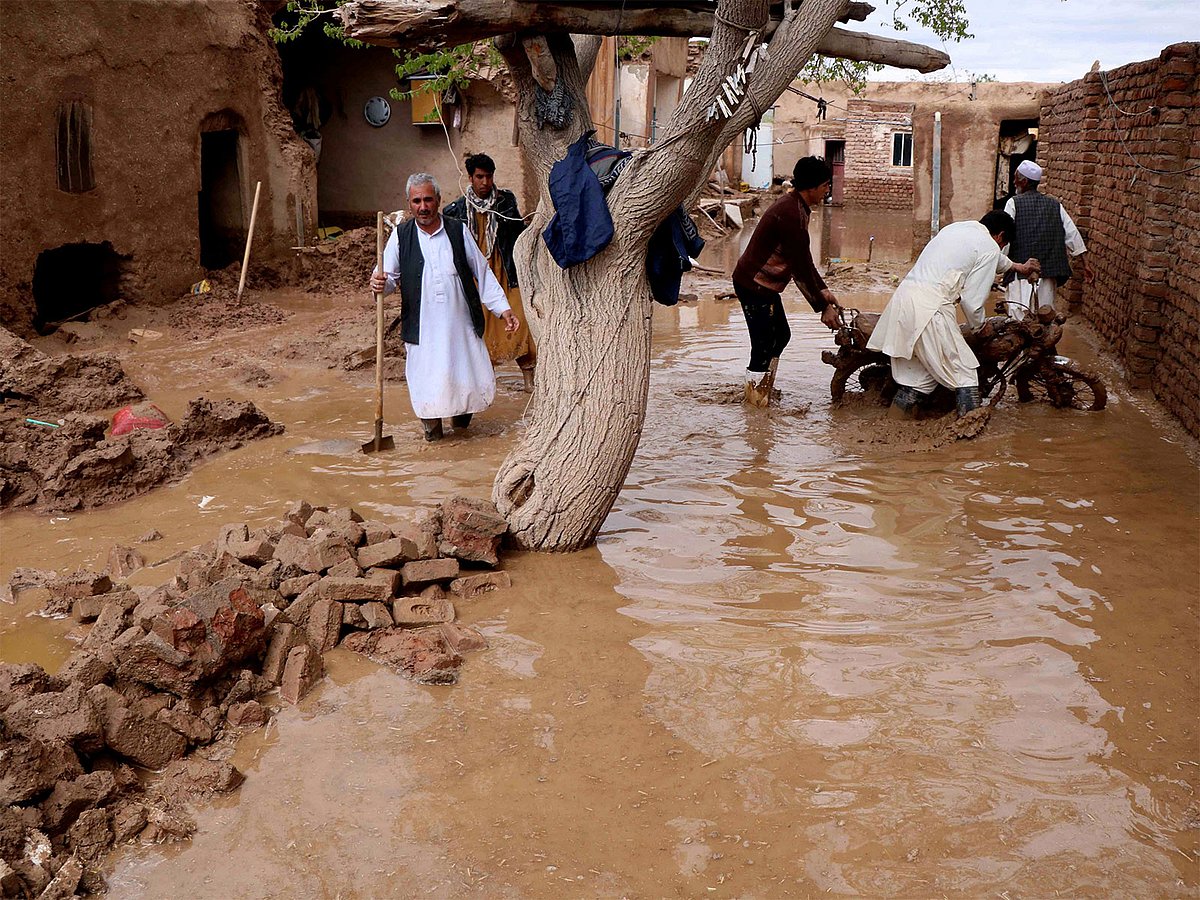 Residents clear debris and wade through floodwater after heavy rains and flash floods hit parts of Afghanistan. 