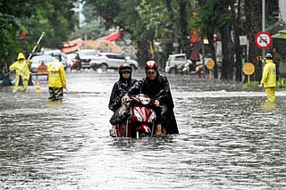 A man pushes his motorbike on a flooded street due to heavy rains caused by Tropical Storm Matmo in Hanoi on October 7, 2025.