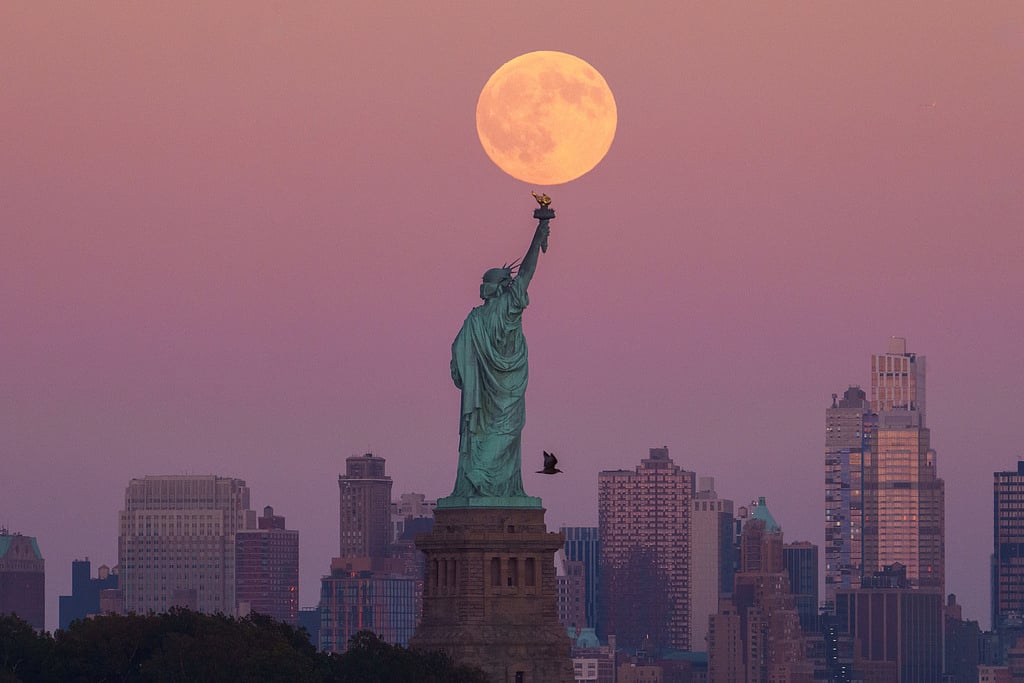 The Harvest Supermoon rises behind the Statue of Liberty and the Brooklyn skyline, Monday, Oct. 6, 2025, in Jersey City, New Jersey.  