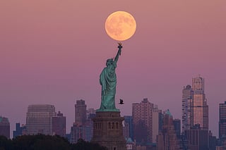 The Harvest Supermoon rises behind the Statue of Liberty and the Brooklyn skyline, Monday, Oct. 6, 2025, in Jersey City, New Jersey.  