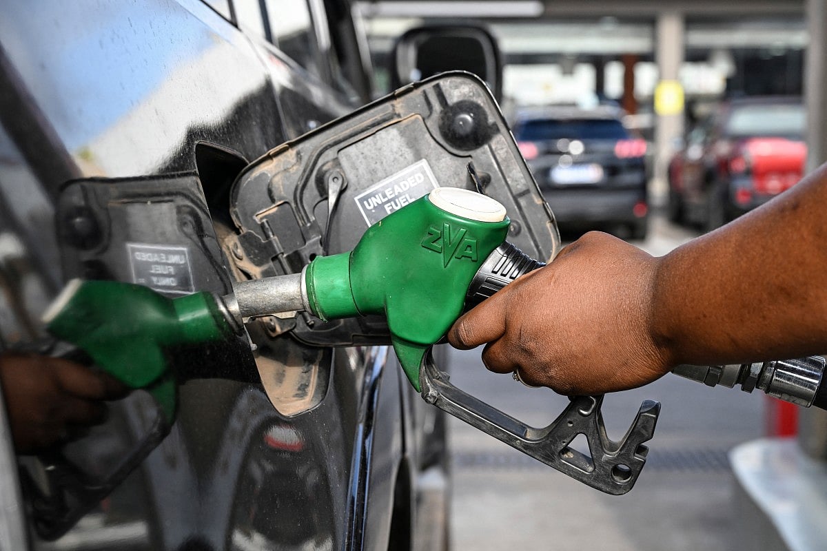 A pump attendant pumps fuel into a car at a service station on October 7, 2025.