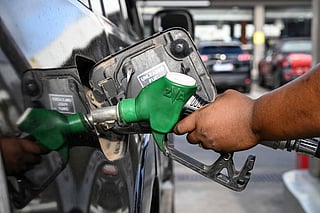 A pump attendant pumps fuel into a car at a service station on October 7, 2025.