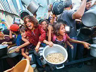 Palestinians shove to receive a hot meal from a charity kitchen in the Nuseirat refugee camp in the Israel-besieged Gaza Strip.