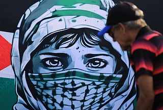 Demonstrators show a sign depicting a person wearing a keffiyeh with the Palestinian flag during a march in Medellin, Colombia on October 7, 2025, on the second anniversary of the deadly Hamas-led attack on Israel which sparked a retaliatory offensive in Gaza.