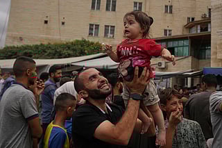 Palestinians celebrate following the announcement that Israel and Hamas have agreed to the first phase of a peace plan to pause the fighting, outside Al Aqsa Hospital in Deir Al Balah, central Gaza Strip on Oct. 9, 2025. 