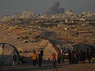 Displaced Palestinians walk along the coastal road, backdropped by smoke rising into the sky in Gaza City on Wednesday October 8.