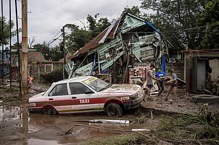 Neighbours gather around a damaged house after heavy rainfall in Poza Rica, Veracruz state, Mexico, Saturday, Oct. 11, 2025.  