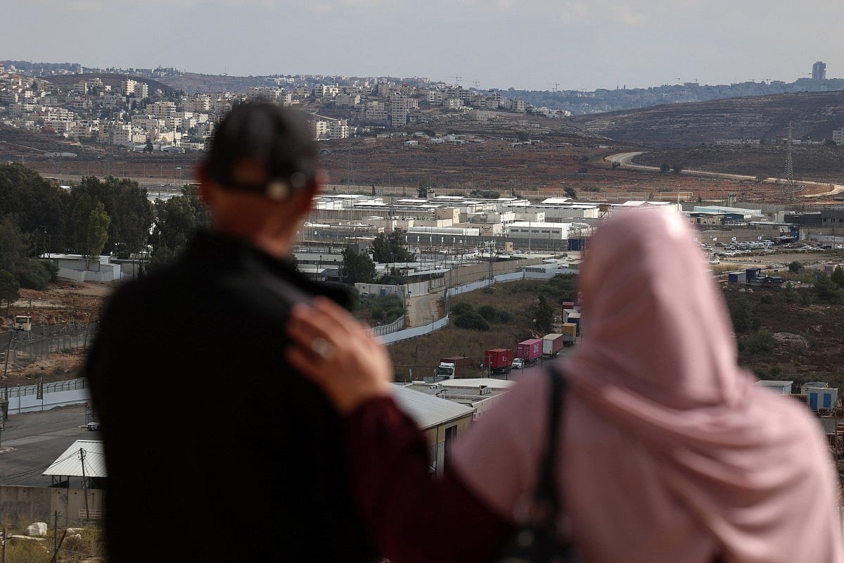 Relatives of a Palestinian prisoner stare at the Ofer military prison complex, located between Ramallah and Beitunia in the occupied West Bank, on October 12, 2025, ahead of an exchange of Israeli hostages and Palestinian prisoners.