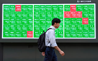 A man walks past an electronic quotation board displaying the Nikkei 225 stock prices on the Tokyo Stock Exchange in Tokyo on October 14, 2025.