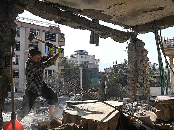 An Afghan man removes debris from a house, which was damaged after an air strike during cross-border clashes between Afghanistan and Pakistan, in Kabul. 