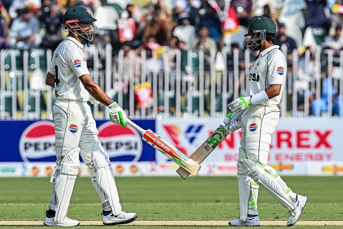 Pakistan's captain Shan Masood (L) and his teammate Babar Azam bump their bats during the first day of the second Test cricket match against South Africa at the Rawalpindi Cricket Stadium in Rawalpindi on October 20, 2025.