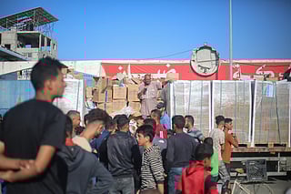 Displaced Palestinians gather around a truck to receive aid supplies that entered Gaza in the morning at the Nuseirat refugee camp in the central Gaza Strip, on October 20, 2025.