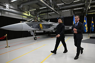 Swedish Prime Minister Ulf Kristersson (R) and Ukrainian President Volodymyr Zelensky walk past a Gripen fighter jet after they delivered a joint press conference in Linkoping, Sweden, on October 22, 2025.