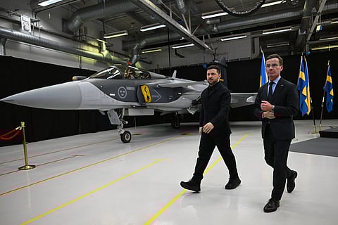 Swedish Prime Minister Ulf Kristersson (R) and Ukrainian President Volodymyr Zelensky walk past a Gripen fighter jet after they delivered a joint press conference in Linkoping, Sweden, on October 22, 2025.