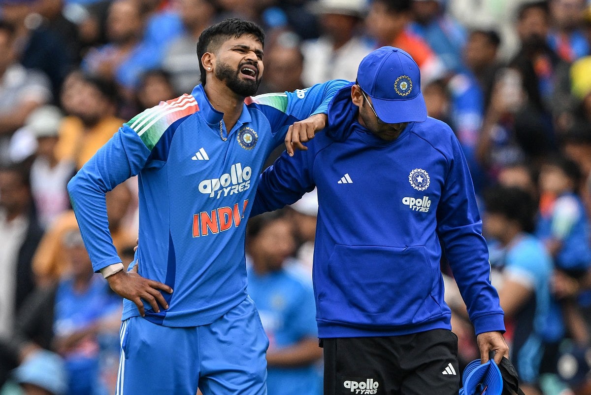 India's Shreyas Iyer (L) reacts in pain after falling on the ground while taking a catch to dismiss Australia's Alex Carey during the third ODI at the Sydney Cricket Ground in Sydney on October 25, 2025.