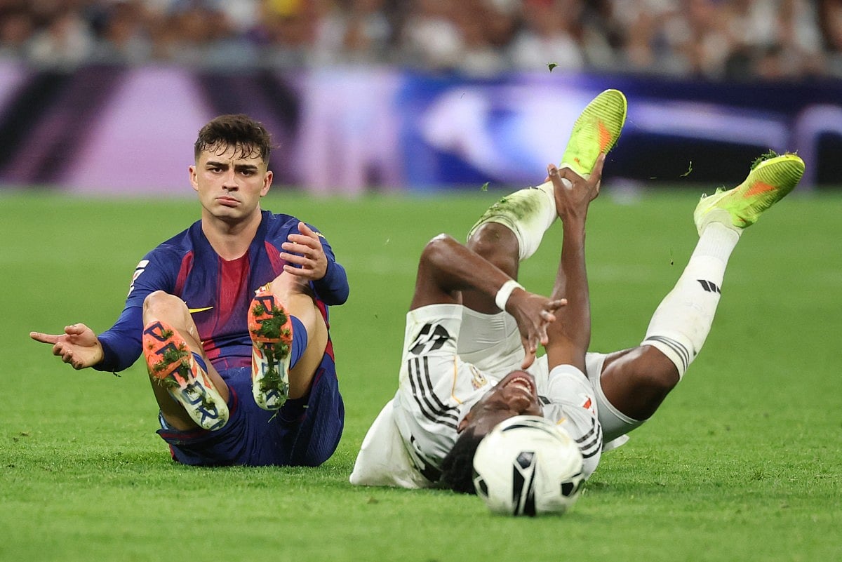 Barcelona's Spanish midfielder #08 Pedri (L) fouls Real Madrid's French midfielder #14 Aurelien Tchouameni during the Spanish league football match between Real Madrid CF and FC Barcelona at Santiago Bernabeu Stadium in Madrid on October 26 , 2025.