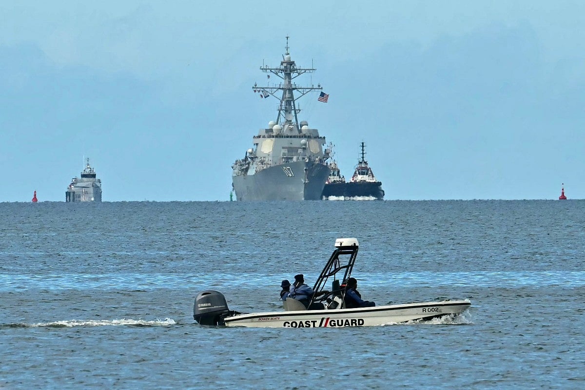 A speedboat of the Trinidad and Tobago Coast Guard patrols as the USS Gravely warship is seen at a distance from Port of Spain on October 26, 2025.