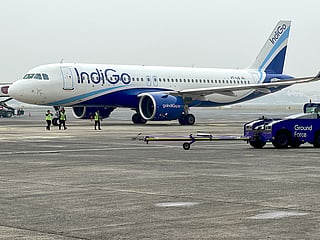 Ground staff walk past an Indigo airlines aircraft taxiing in the apron at the Netaji Subhash Chandra Bose International airport in Kolkata. 
