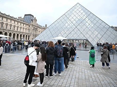People queue outside the Louvre museum in Paris.