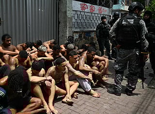 Police officers guard alleged criminals arrested during the Operacao Contencao (Operation Containment) at the Vila Cruzeiro favela, in the Penha complex, in Rio de Janeiro, Brazil, on October 28, 2025.
