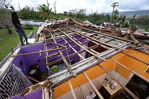 A man stands on what is left of the roof of his neighbor following the passage of Hurricane Melissa, in longwood, St Elizabeth, Jamaica on October 29, 2025.