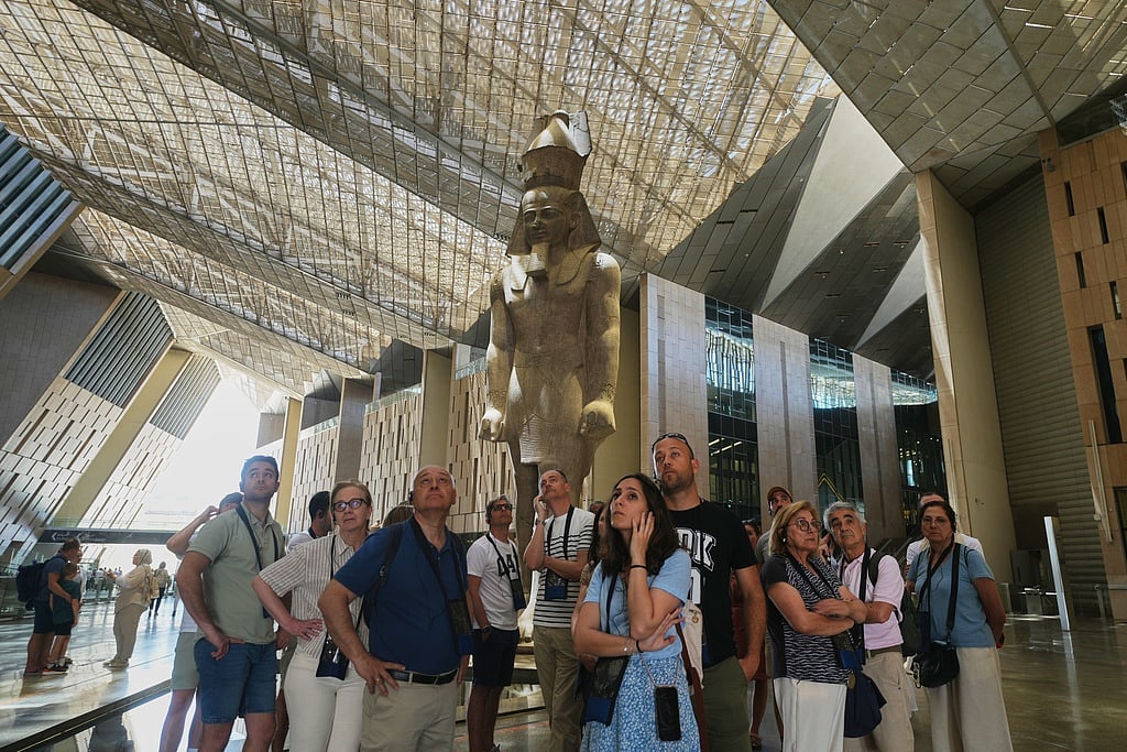 Tourists stand under the statue of Pharaoh Ramses II, at the Grand Egyptian Museum in Giza, Egypt, Friday, May 23, 2025.