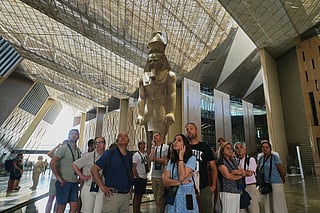Tourists stand under the statue of Pharaoh Ramses II, at the Grand Egyptian Museum in Giza, Egypt, Friday, May 23, 2025.