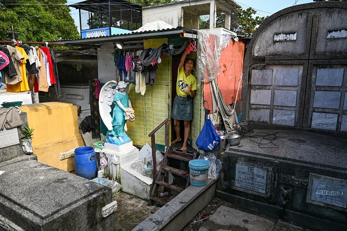 This photo taken on October 21, 2025 shows resident Laileah Cuetara fixing her laundry outside her makeshift house at Manila North Cemetery in Manila.
