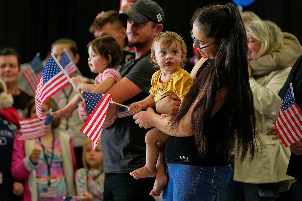 Afrikaner refugees from South Africa holding American flags arrive, May 12, 2025, at Dulles International Airport in Dulles, Va.