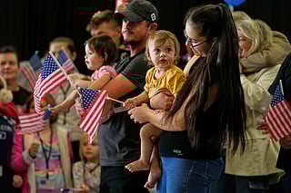 Afrikaner refugees from South Africa holding American flags arrive, May 12, 2025, at Dulles International Airport in Dulles, Va.  