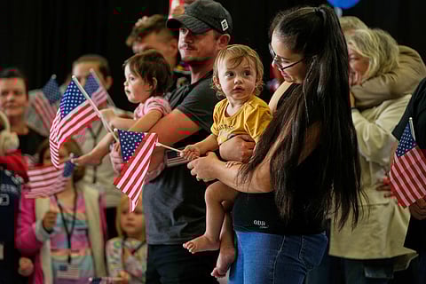 Afrikaner refugees from South Africa holding American flags arrive, May 12, 2025, at Dulles International Airport in Dulles, Va.  