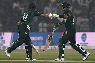 Pakistan's Sahibzada Farhan (L) and Babar Azam (R) bump up during the third and final Twenty20 international cricket match between Pakistan and South Africa at the Gaddafi Stadium in Lahore on November 1, 2025.