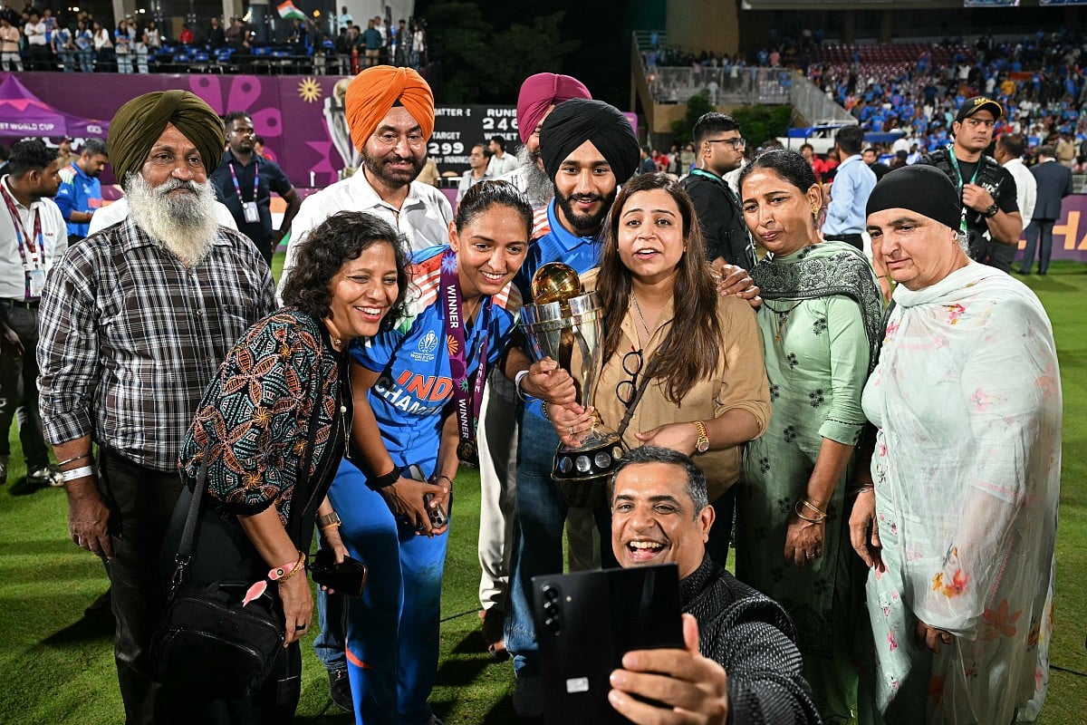 India's captain Harmanpreet Kaur (C) poses with her family members after winning the ICC Women's Cricket World Cup 2025 one-day international (ODI) final match between India and South Africa at the DY Patil Stadium in Navi Mumbai on November 3, 2025.