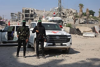 Palestinian Hamas militants stand near a International Red Cross (ICRC) vehicle, as a search for the bodies of killed Israeli hostages takes place, in Gaza City on November 2, 2025.