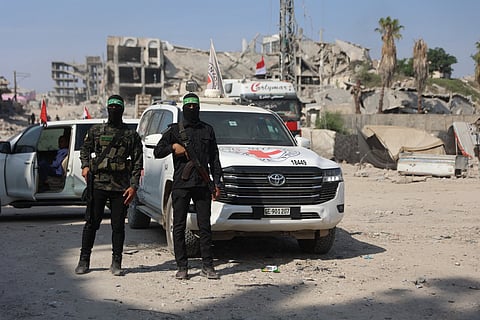 Palestinian Hamas militants stand near a International Red Cross (ICRC) vehicle, as a search for the bodies of killed Israeli hostages takes place, in Gaza City on November 2, 2025.